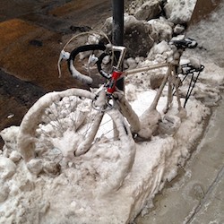 bike covered in snow attached to a pole